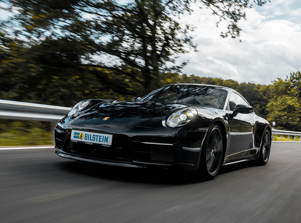 Porsche 992 von vorne, der mit BILSTEIN Gewindefahrwerk auf einer Landstra?e im Wald f?hrt