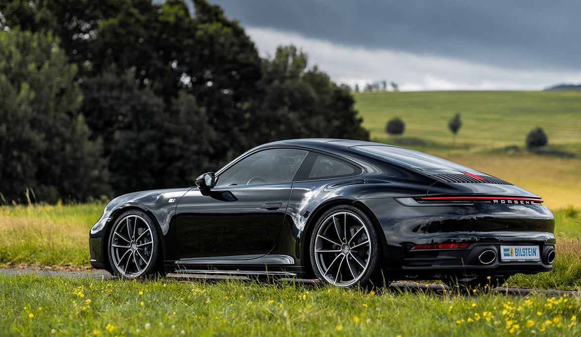 A lowered Porsche 992 stands on a green field